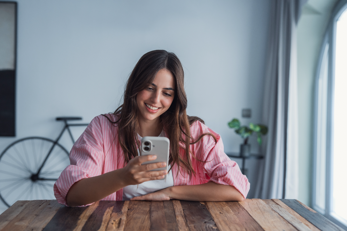 Joven sonriendo mientras usa su celular